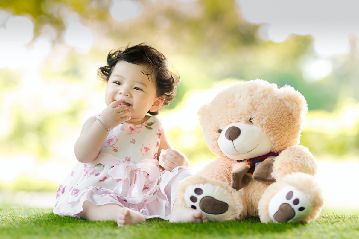 A Baby Sitting Next To A Teddy Bear