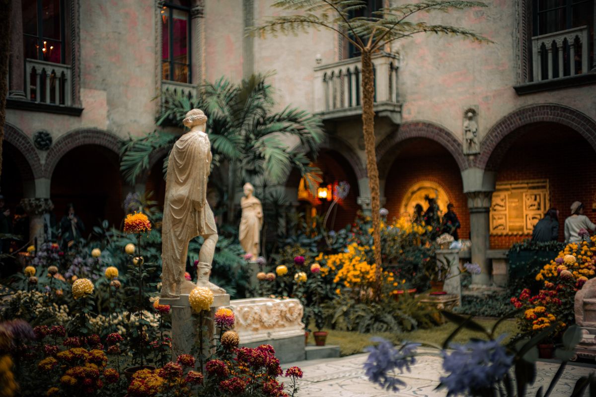 A Garden With Flowers And Statues