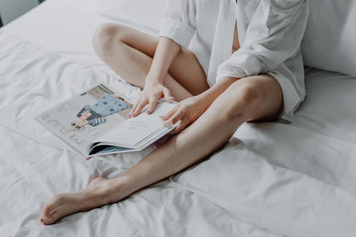 A Woman Lying On A Bed Reading A Book