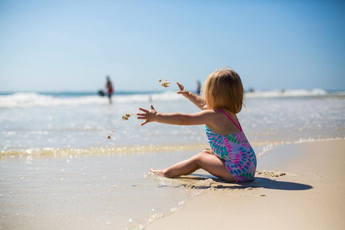 A Child Sitting On A Beach