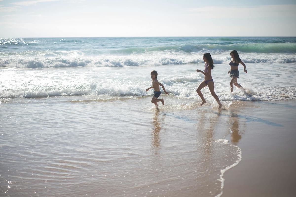 A Group Of Children Running On A Beach